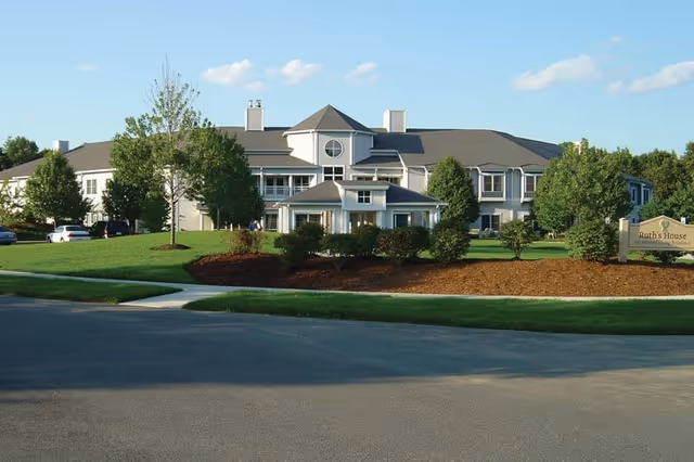 Exterior view of Ruth's House senior living facility with manicured lawn and sign.