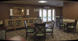 Interior dining room with tables and chairs, sideboard, and decorative lamps.