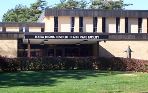 This is the front exterior of Maria Regina Residence Health Care Facility with a sign.