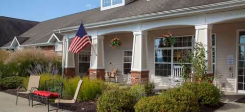 Front exterior of Brookdale Ithaca AL with flag, porch columns, and outdoor seating.