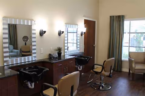 Interior view of a senior living facility hair salon with mirrors, chairs, and washing basins.