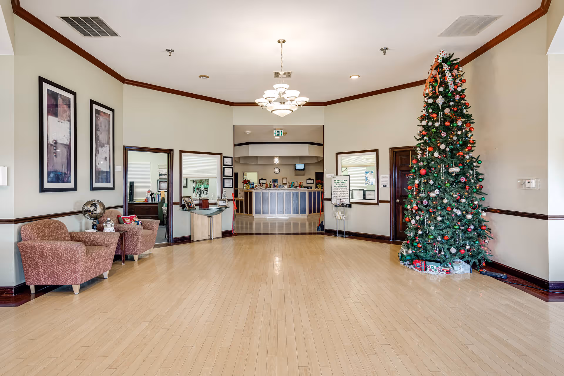 Spacious decorated senior living lobby with seating, a reception desk, and a tall Christmas tree.