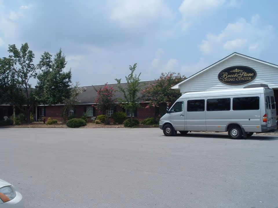 Exterior front of Brook Stone Living Center with a silver passenger van parked in the lot.