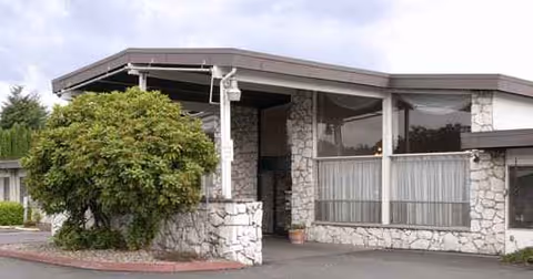 Stone-faced senior living facility front with large windows and a covered entrance.