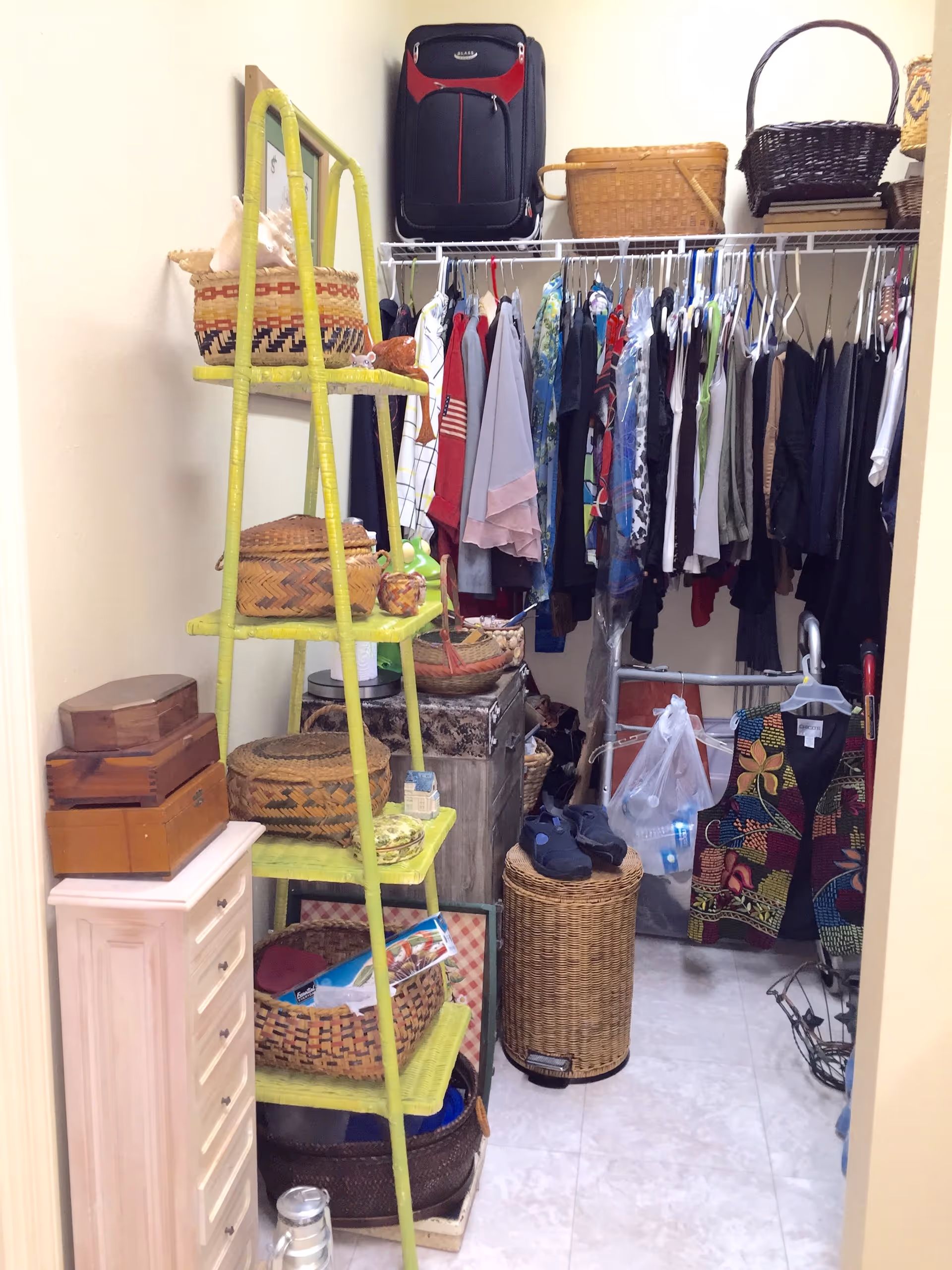 A walk-in closet packed with hanging clothes, baskets, shelving and various storage items.