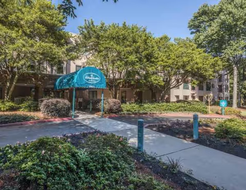 Exterior view of Delmar Gardens of Smyrna with entrance canopy and landscaped walkway.