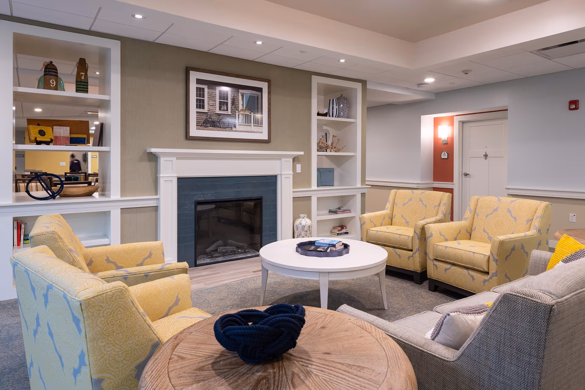 Comfortable common lounge with a fireplace, round coffee tables and several upholstered armchairs.