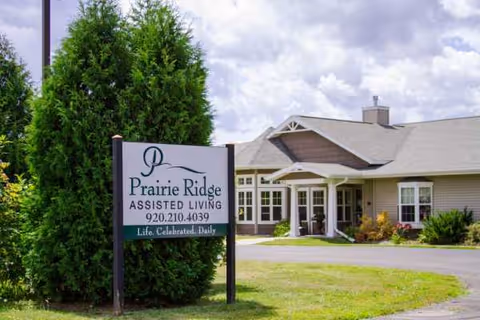 Exterior view of Prairie Ridge Assisted Living with sign, entrance, and landscaped lawn.