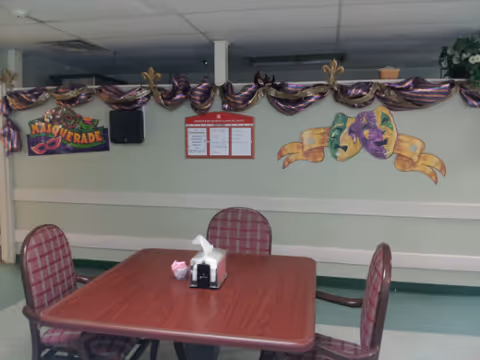 A small dining table with four plaid chairs in a decorated communal room.