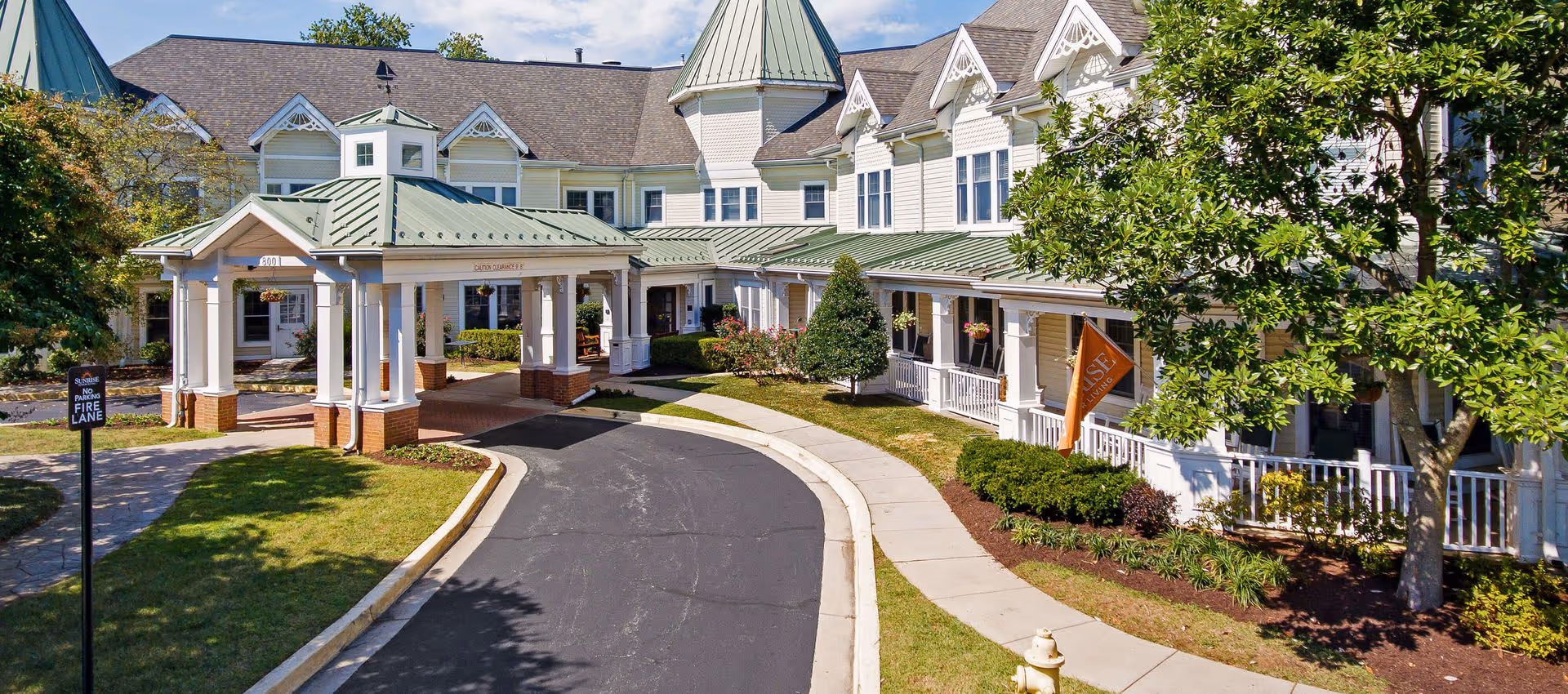 Front entrance of Sunrise of Annapolis with a covered porte-cochère, circular driveway, and landscaped grounds in front of a multi-story building.