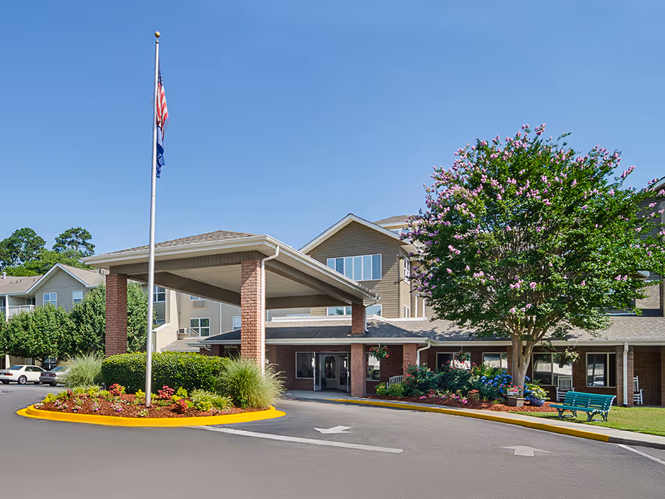 Exterior view of Holiday Columbia Pines, showing entrance, flagpole, landscaped circle, and benches.