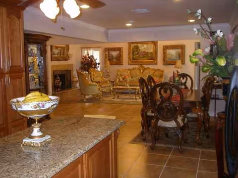 Open living area with dining table, chairs, and sofas in Sunshine Senior Living facility.