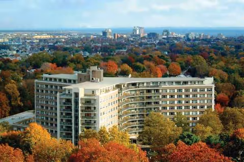 Aerial view of a large modern senior living building surrounded by autumn trees.