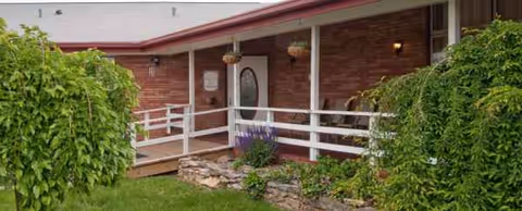 Exterior view of a brick senior facility entrance with a white railing.