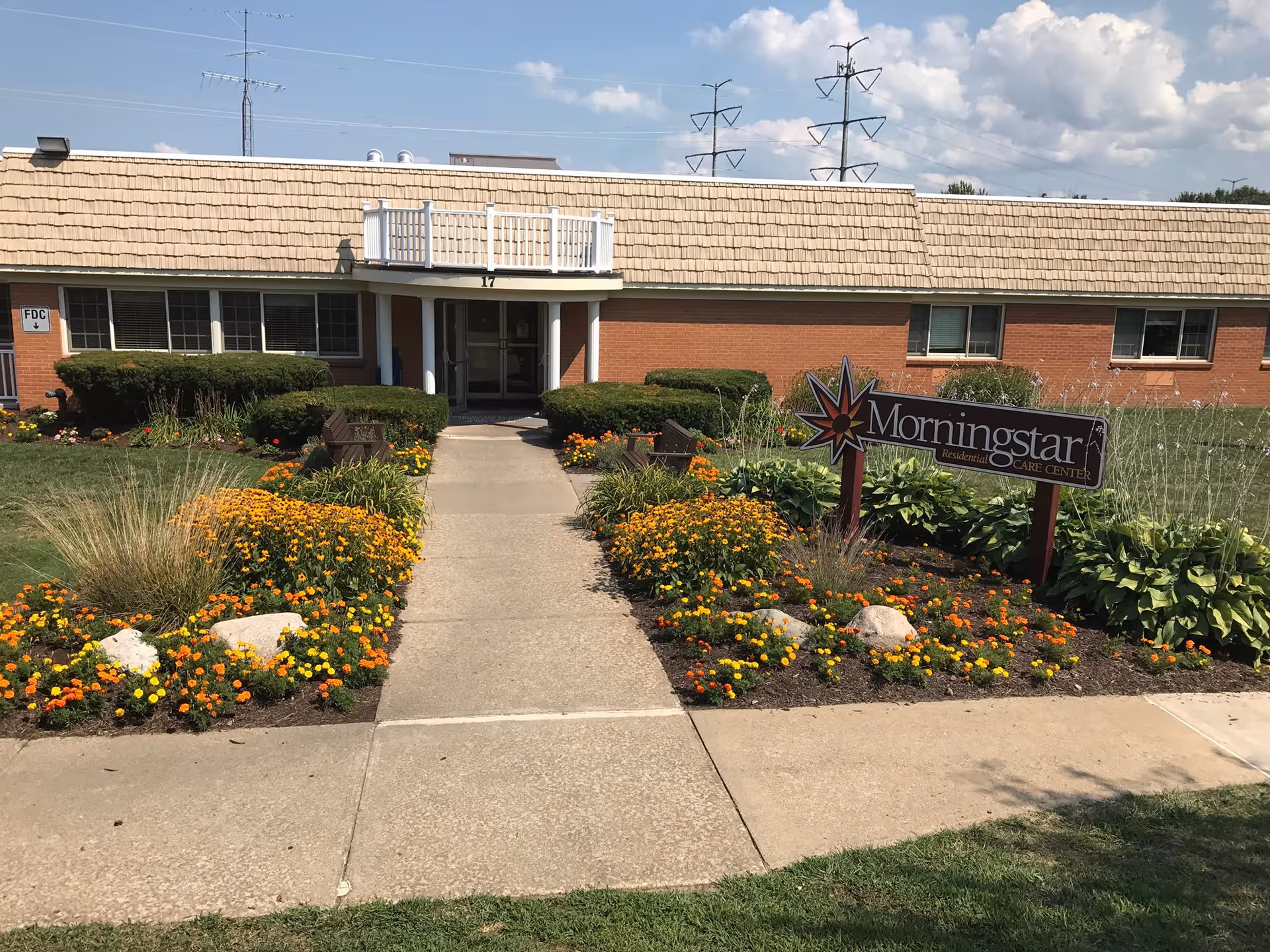 Front entrance of the Morningstar Residential Care Center with a walkway, landscaped flowerbeds and a sign.