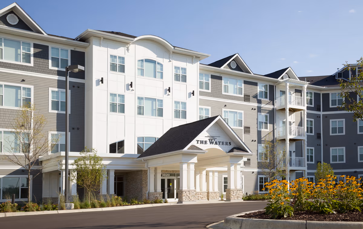 Exterior view of a modern senior living building with a covered entrance and landscaping.