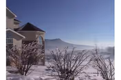 Sunny winter exterior of Sunnyside facility with snow, bare shrubs, and mountains.