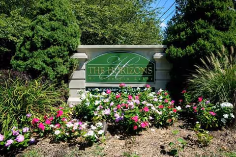 Front entrance sign for Horizons at Franklin Lakes, framed by blooming flowers and lush greenery.