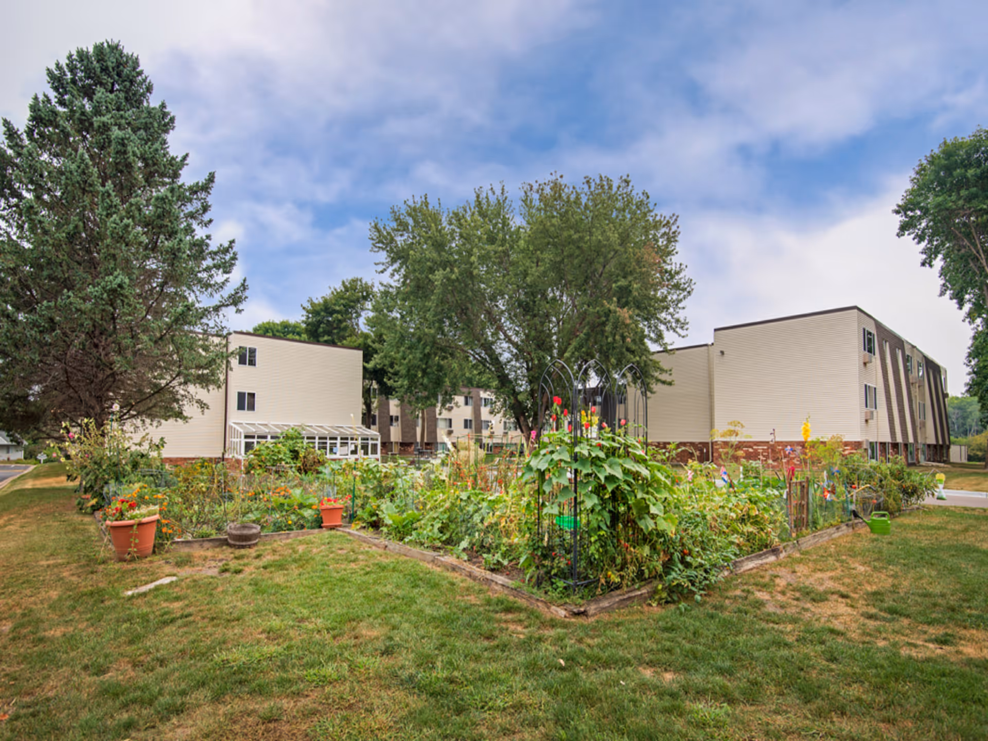 Exterior view of Kilkenny Court showing a beige building and a garden with raised beds.