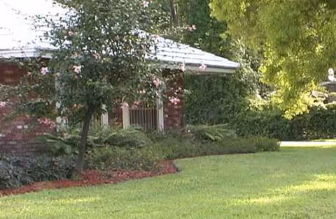 Exterior of a brick Lee Residence with a manicured lawn and trees.