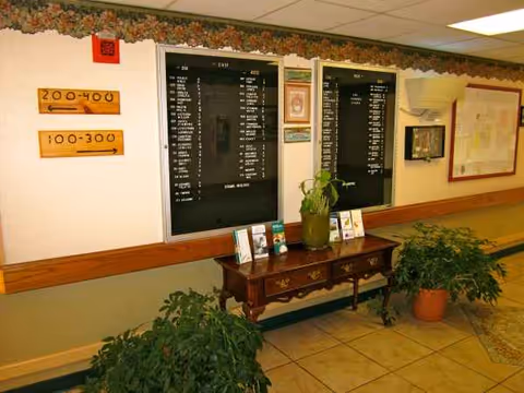 Hallway of Festus Manor with a dark directory board, wooden console, and plants.