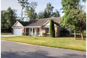 Single-story senior living facility with a front entrance, lawn, and trees.