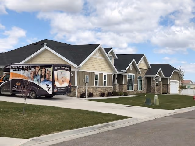 Single-story Lotus Park Care Centers building with multiple pitched gables and a branded van parked in the driveway under a partly cloudy sky.