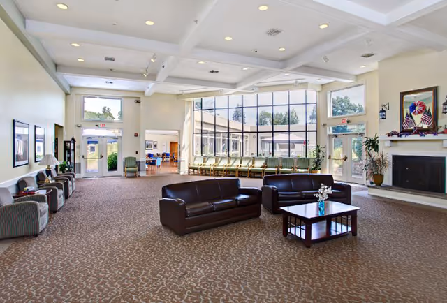 Spacious, well-lit common room with leather sofas, armchairs, a coffee table, large windows and a fireplace.
