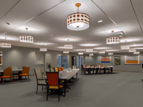 Large open dining room with tables and chairs under modern ceiling lights.