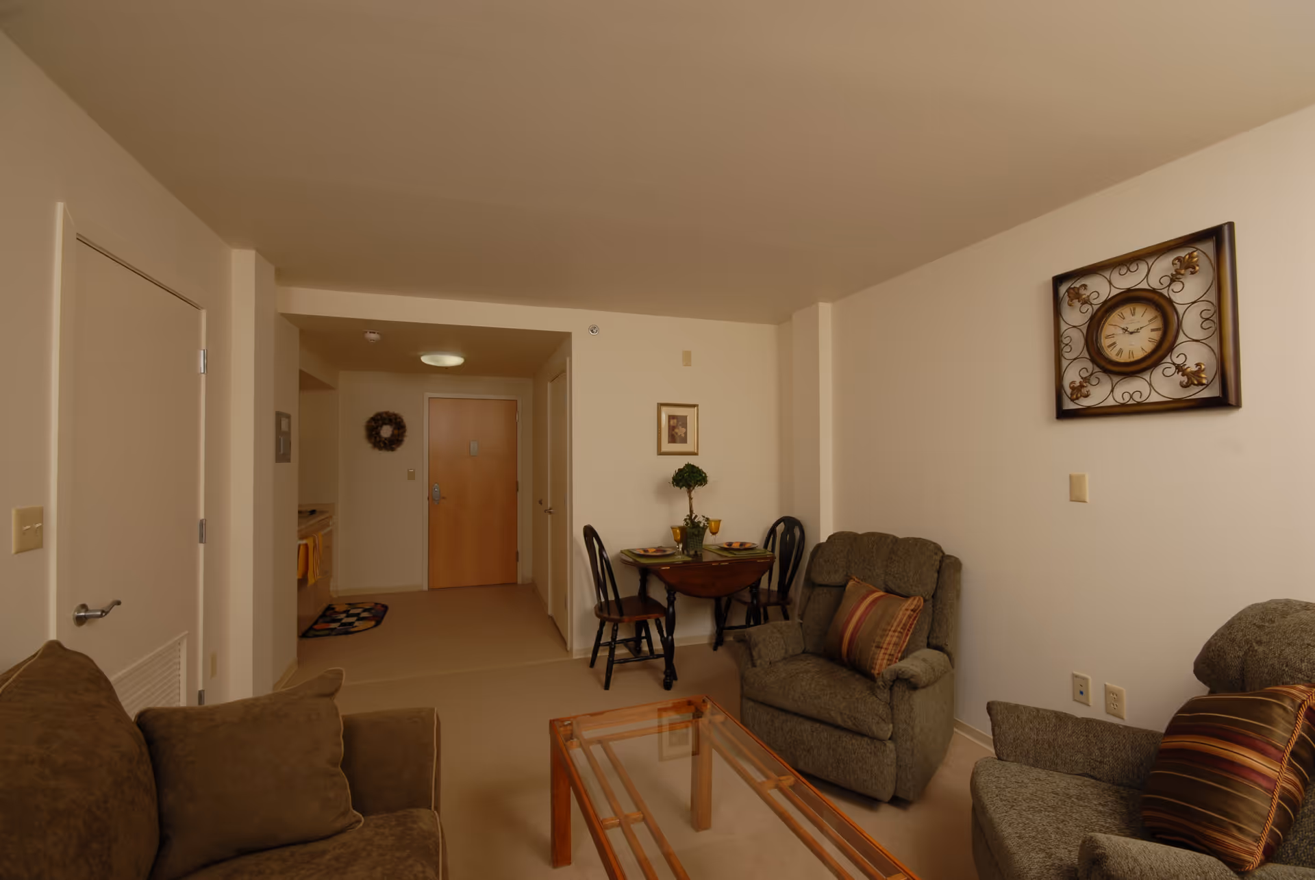 Indoor senior living common area with couches, chairs, and a dining table.