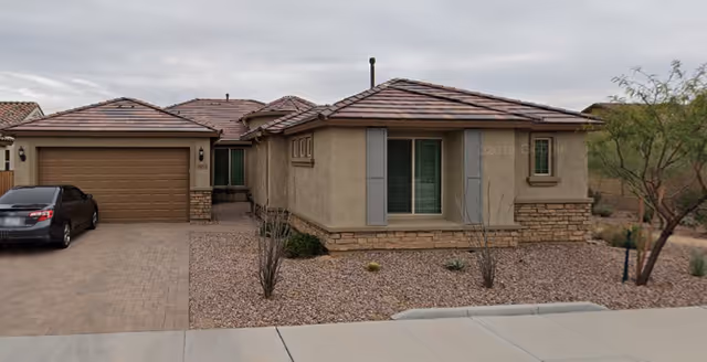 Single-story beige stucco building with a two-car garage and desert landscaping.