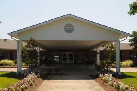 Front view of a senior living facility entrance with a covered driveway and landscaping