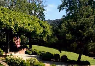 Lush landscaping with a gazebo, American flag, and trees around Oakpark Healthcare Center.