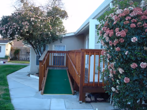 Mercy Adult Care front entrance with wooden ramp and flowering shrubs