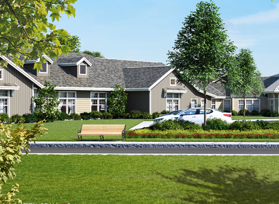 Front exterior of a single-story senior living building with a bench, lawn, trees, and a parked car.