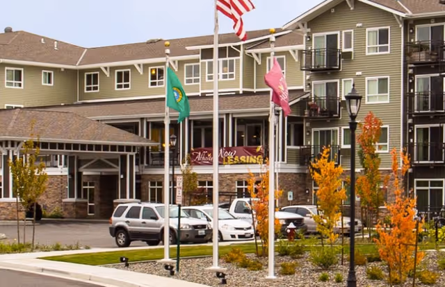 Exterior front of the Affinity at Bellingham building with flagpoles, parked cars, and a landscaped entrance.