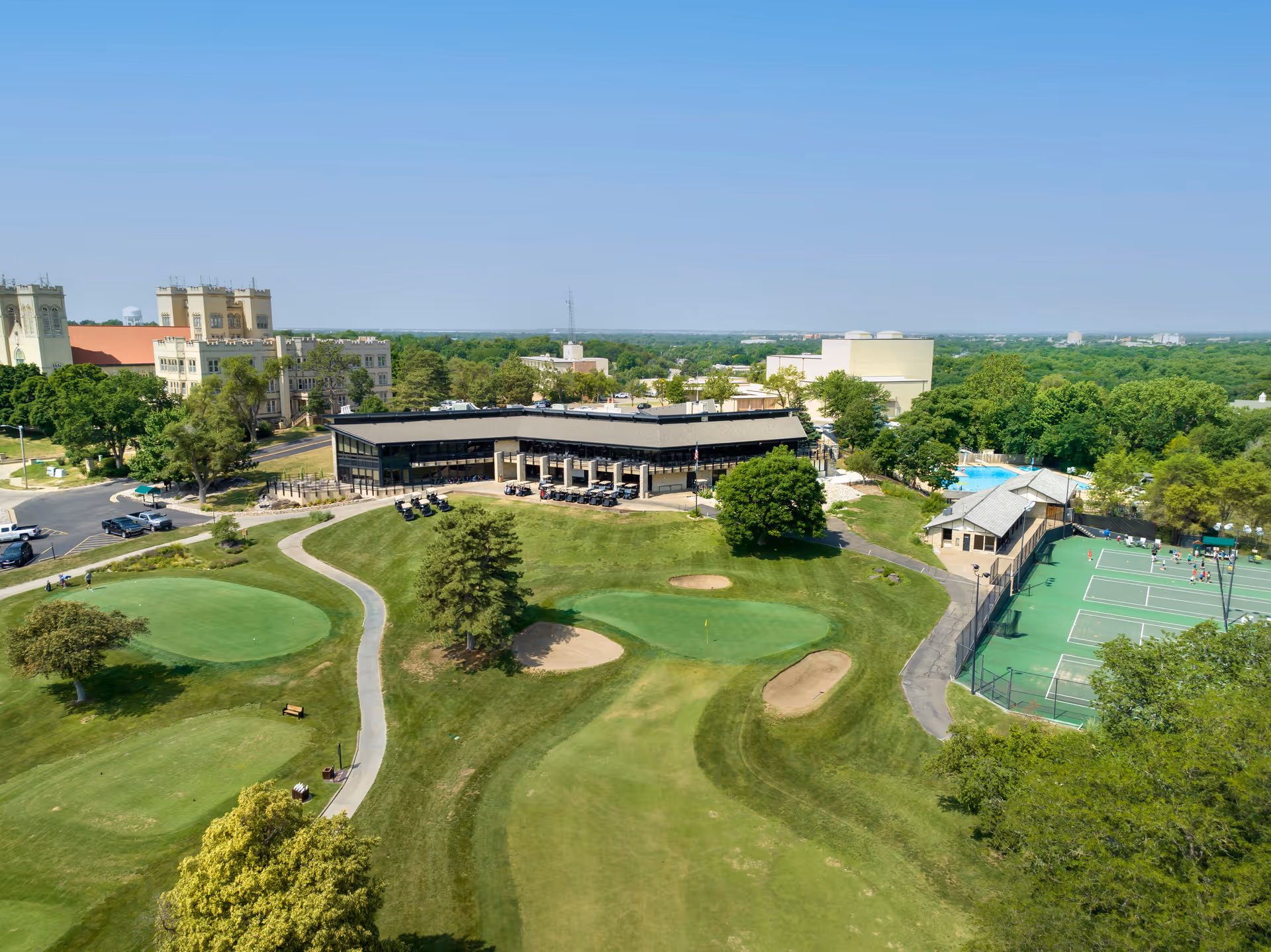 Aerial view of the Brookdale Salina Fairdale grounds showing a clubhouse, golf course greens and bunkers, and nearby tennis courts and pool.