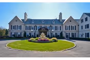 Elegant white mansion-style building with circular driveway, central fountain, and manicured lawn.