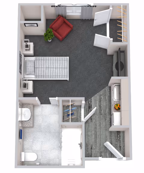 Top-down view of a small apartment floor plan showing a bedroom with a single bed, two nightstands, a red armchair, a plant, and a TV on a stand. Adjacent to the bedroom is a bathroom with a toilet, sink, and shower. There is a small kitchen area with a sink and countertop. The floor transitions from carpet in the bedroom to tile in the bathroom and wood flooring in the kitchen. There are two closets, one near the entrance and one near the bathroom.