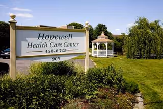 Exterior view of Hopewell Health Care Center sign with gazebo and manicured lawn.