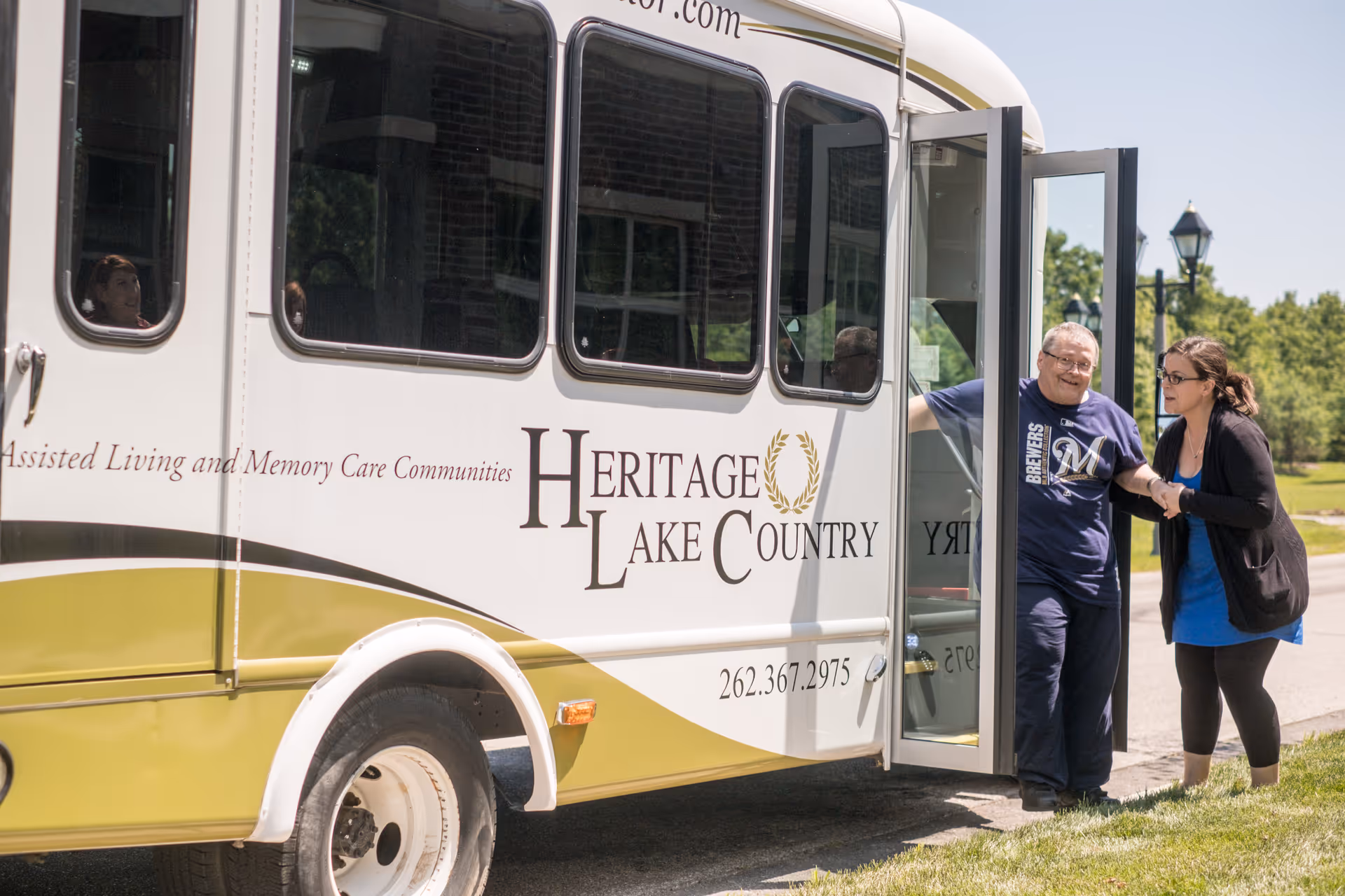 A Heritage Lake Country shuttle with its door open as a man steps off assisted by a staff member.