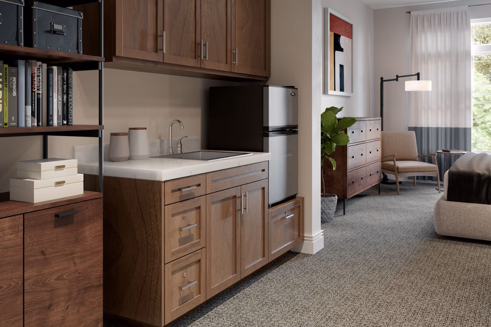 Studio-style interior showing a small kitchenette with wood cabinets and a mini-fridge opening into a furnished living/bedroom area with a dresser, chair, and bed.