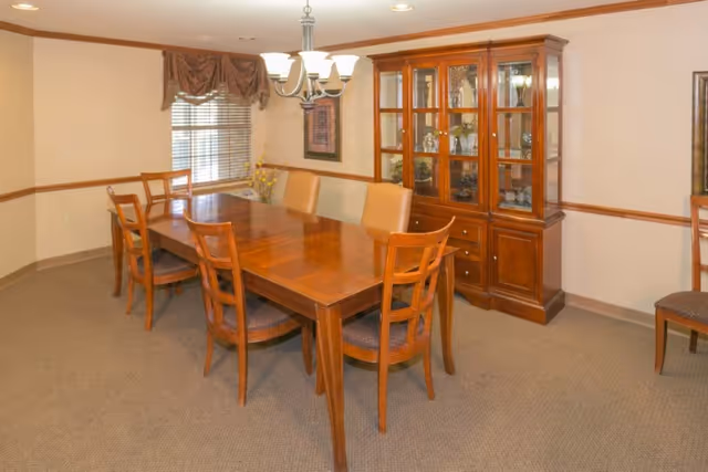 Dining room with a wooden table, six chairs, a glass-front china cabinet and a chandelier.