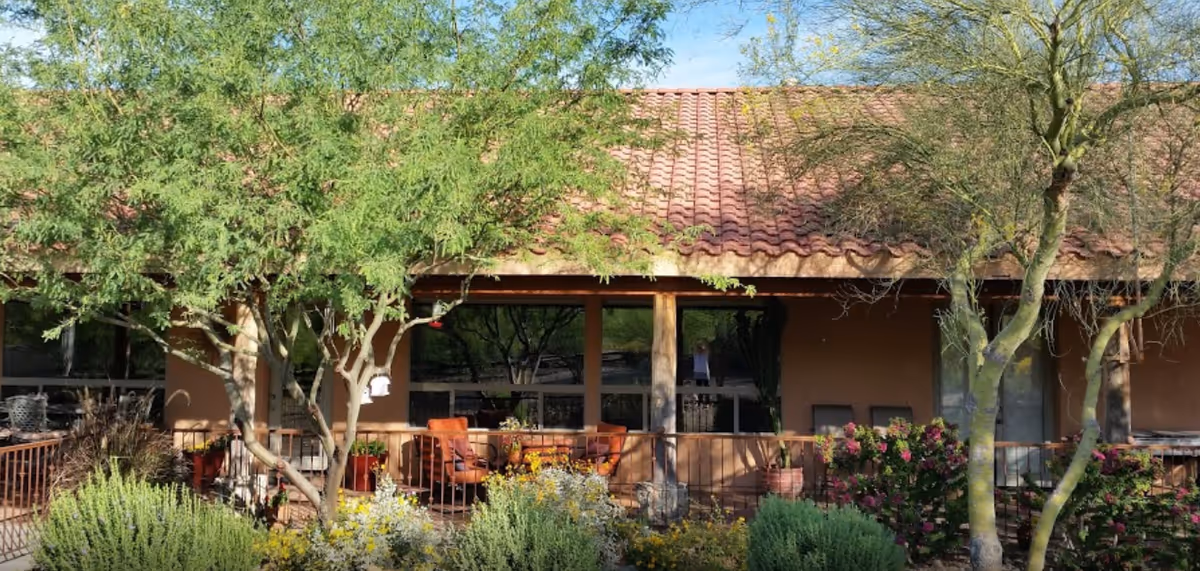 Exterior view of Heaven Can Wait senior living facility with a shaded patio and trees.