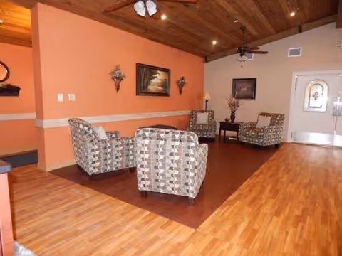 Warm, open living room with patterned chairs, wood floors, and a ceiling fan.