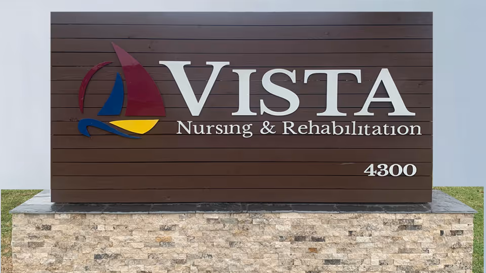 A large outdoor sign for Vista Nursing & Rehabilitation with a colorful sailboat logo on a wooden background, mounted on a stone base with the number 4300.