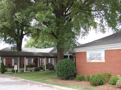 Exterior view of Silas Creek Rehabilitation Center, brick building with sign and trees.