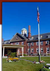 Front exterior of The Berkeley Retirement Home and Nursing Center with flagpole and flowers.