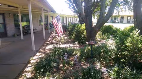 Exterior view of Mount Hope Nursing Center with walkway, flag, and landscaped garden.