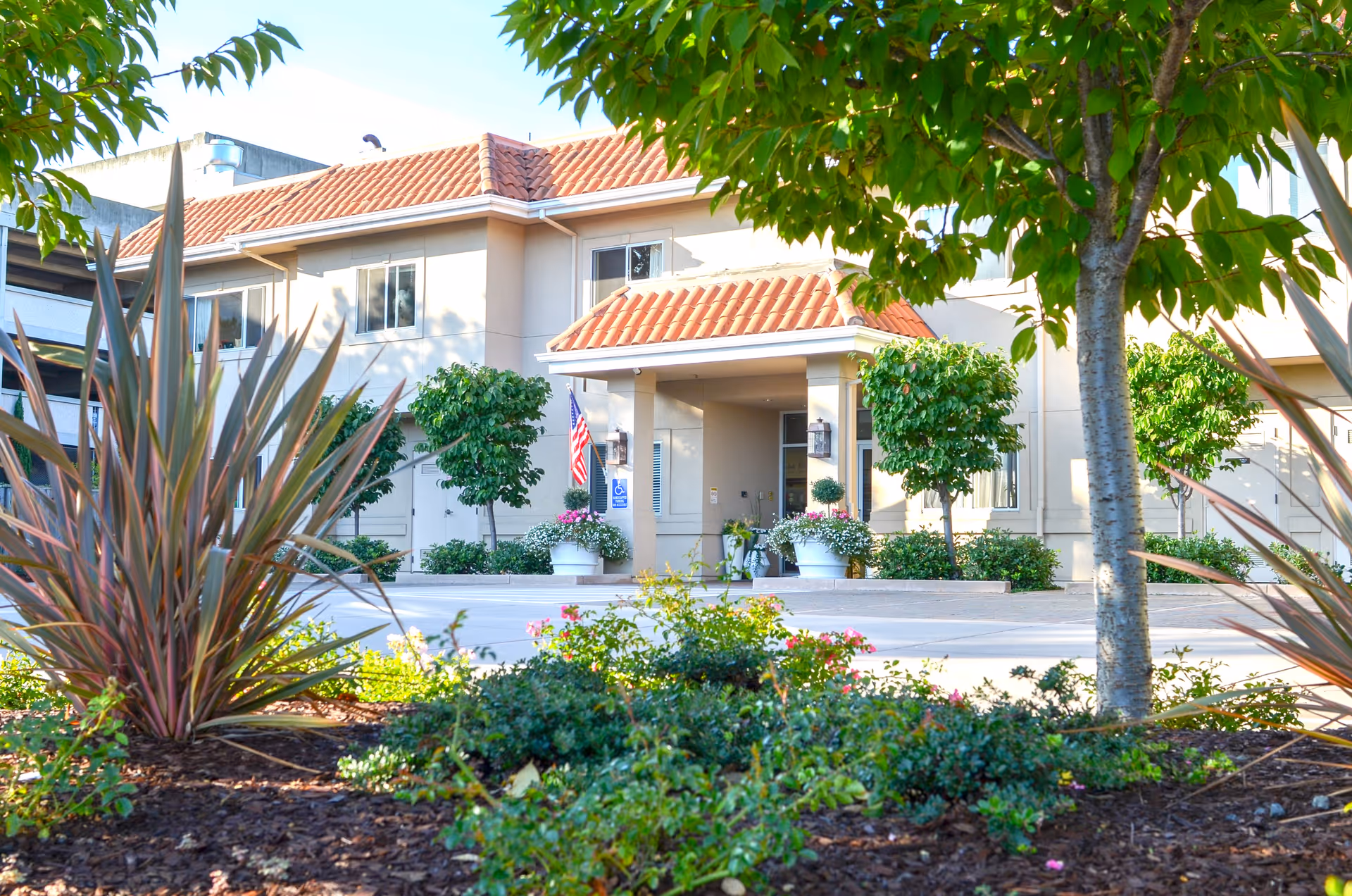 Exterior view of Mills Estate Villa entrance with landscaping and an American flag.